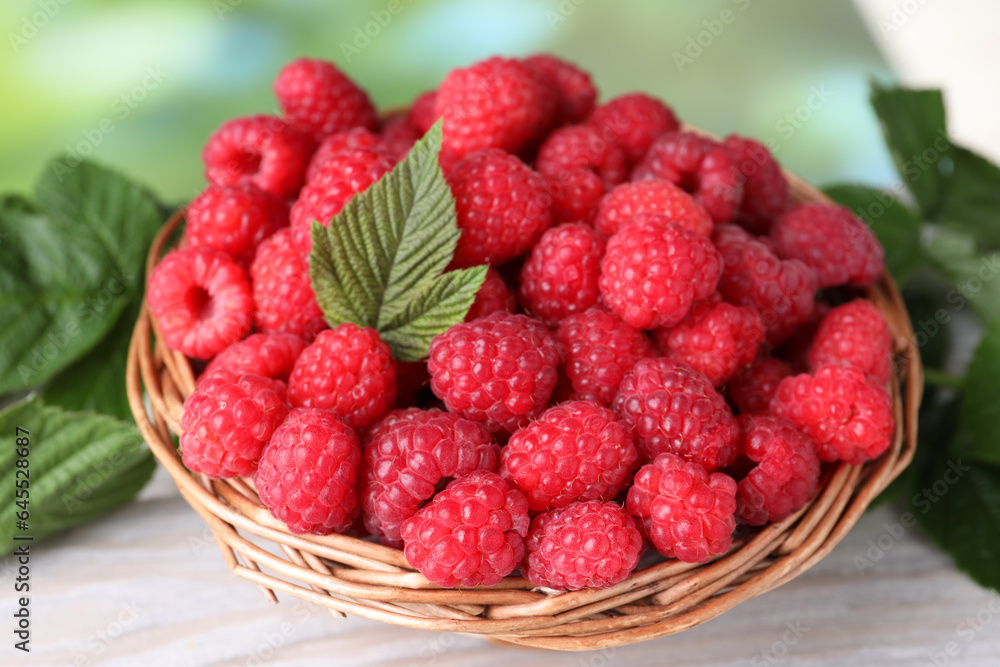 Tasty ripe raspberries and green leaves on light table, closeup Tasty ripe raspberries and green leaves on light table, closeup