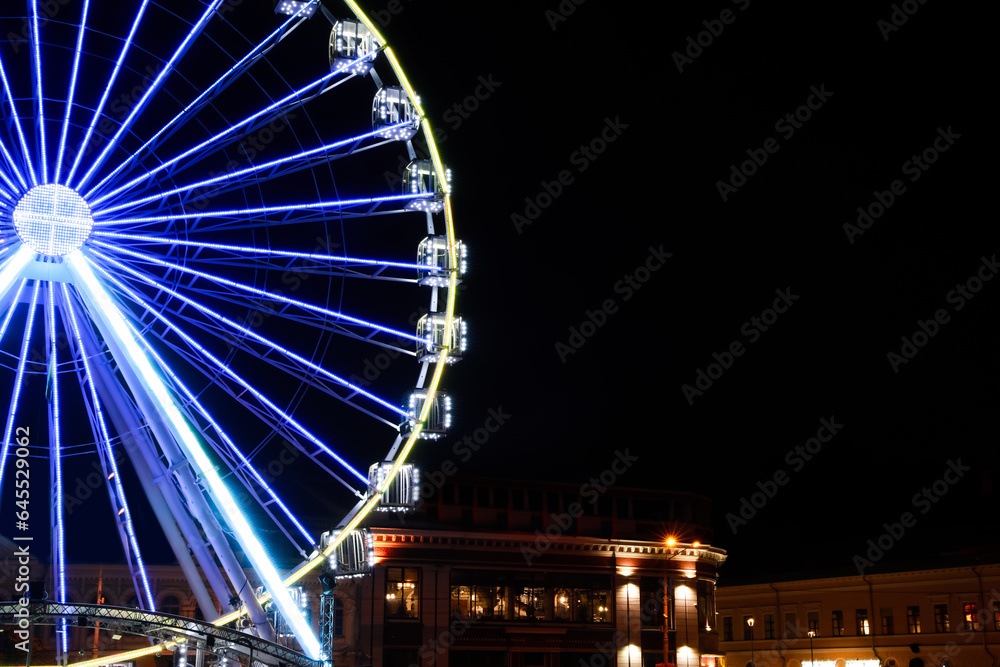 Beautiful glowing Ferris wheel in city at night. Space for text