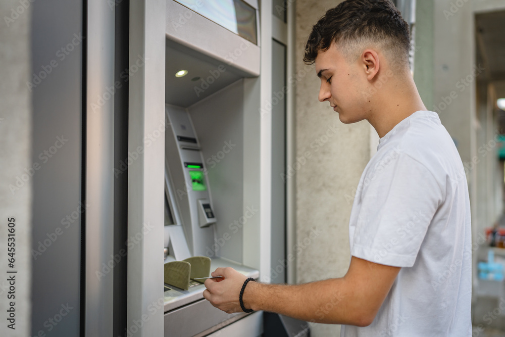 man teenage student using credit card and withdraw cash at the ATM man teenage student using credit card and withdraw cash at the ATM