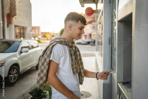 Φωτογραφία man teenage student using credit card and withdraw cash at the ATM