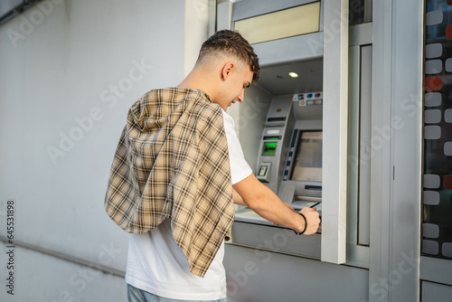 man teenage student using credit card and withdraw cash at the ATM