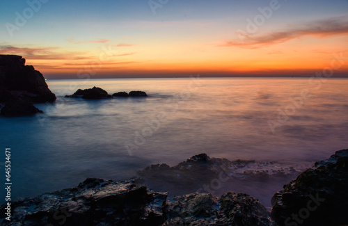 sunset The last light of the day The sky is getting darker At the edge of the coastal rocks Soft sea waves with ND filter © Niranchai