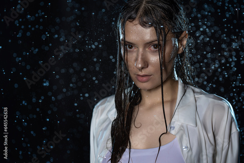 Fotografie young woman in the rain, getting wet through, wet clothes and water running down her face