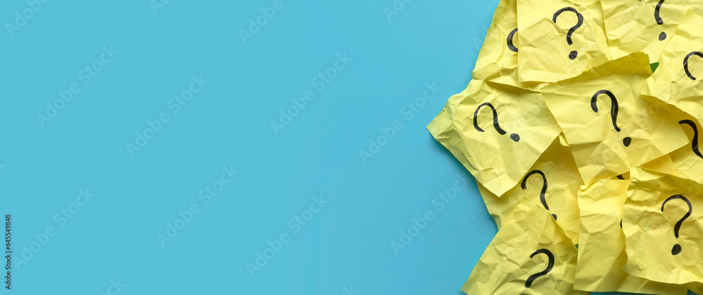Fototapeta premium Questions and answers concept QnA. Yellow and crumpled memo note written with questions symbol over a blue background with copy space.