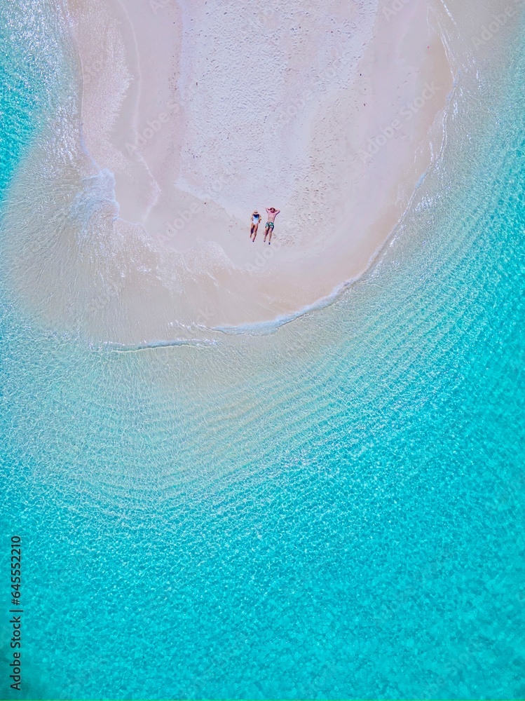 couple of men and women at a white sandbank in the ocean of Koh Lipe Island Southern Thailand, with turqouse colored ocean and white sandy beach sandbar at Ko Lipe on a sunny day