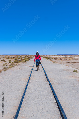 Traveling girl walking along the train tracks.