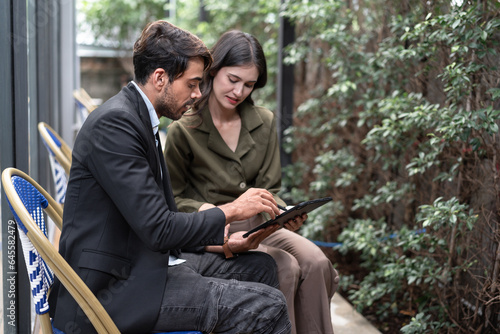 Caucasian businessman checking work on tablet of Asia businesswoman at outdoor office  © chachamp