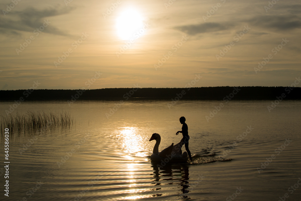 sunset over the lake, people walk on the water, children play with an inflatable swan