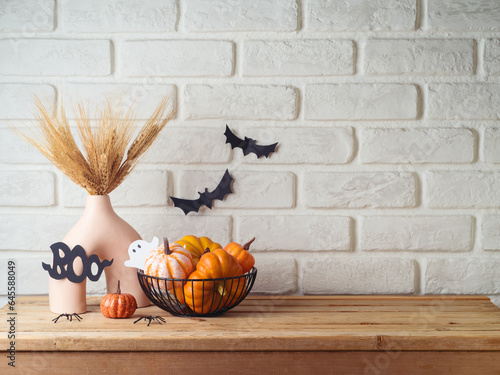 Halloween background with modern vase and decoration on wooden table over brick wall. Empty space for product display