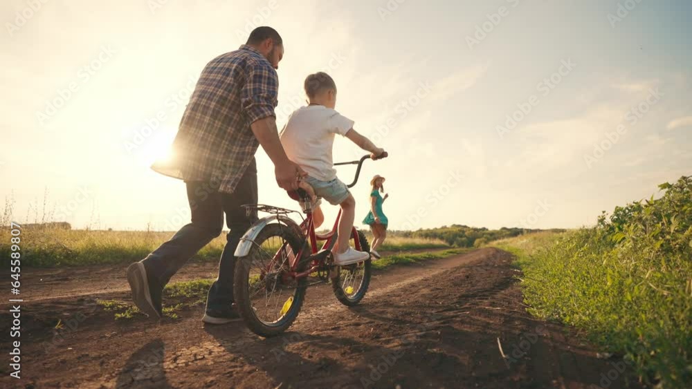 Silhouette mom dad teach son ride bike on field in village near car at ...