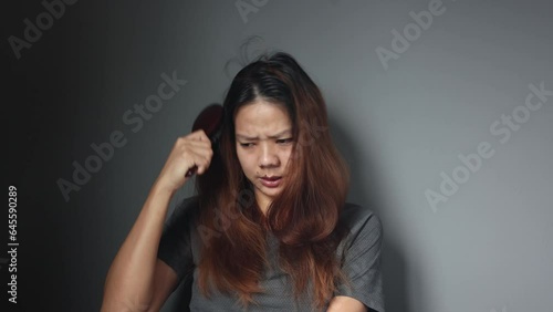 Asian girl with a comb and problem hair on gray background. Asian young woman holding brush, hairbrush with long loss hair problem after brushing.