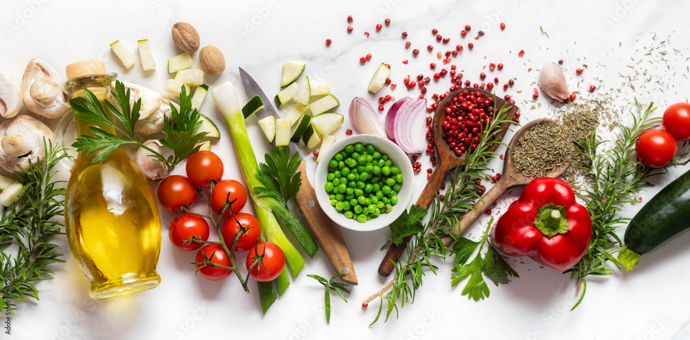 Healthy food cooking ingredients background with fresh vegetables, herbs, spices and olive oil on marble table top view