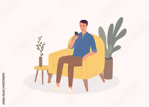 One Smiling Young Man Sitting On Sofa While Using His Mobile Phone. Full Length.