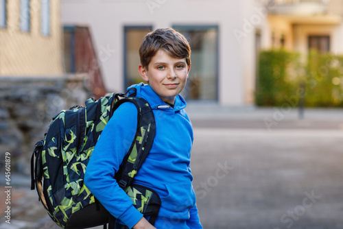 Happy preteen kid boy with satchel, walking. Schoolkid on the way to middle or high school. Excited child outdoors on school yard. Back to school.