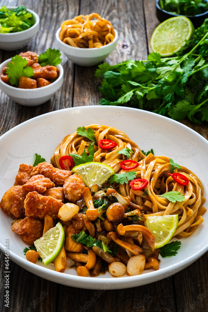 Asian food - chicken nuggets, noodles and fried shimeji mushrooms on wooden table
