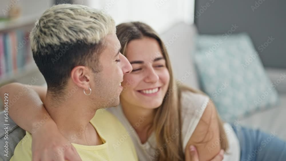 Beautiful couple hugging each other sitting on sofa at home Beautiful couple hugging each other sitting on sofa at home