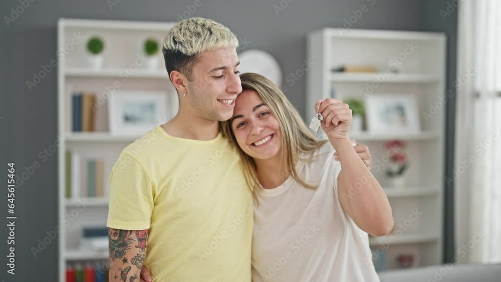 Beautiful couple hugging each other holding keys at home Beautiful couple hugging each other holding keys at home