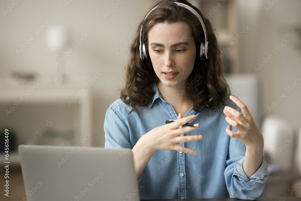 Serious gen Z student girl in headphones talking on video call at ...