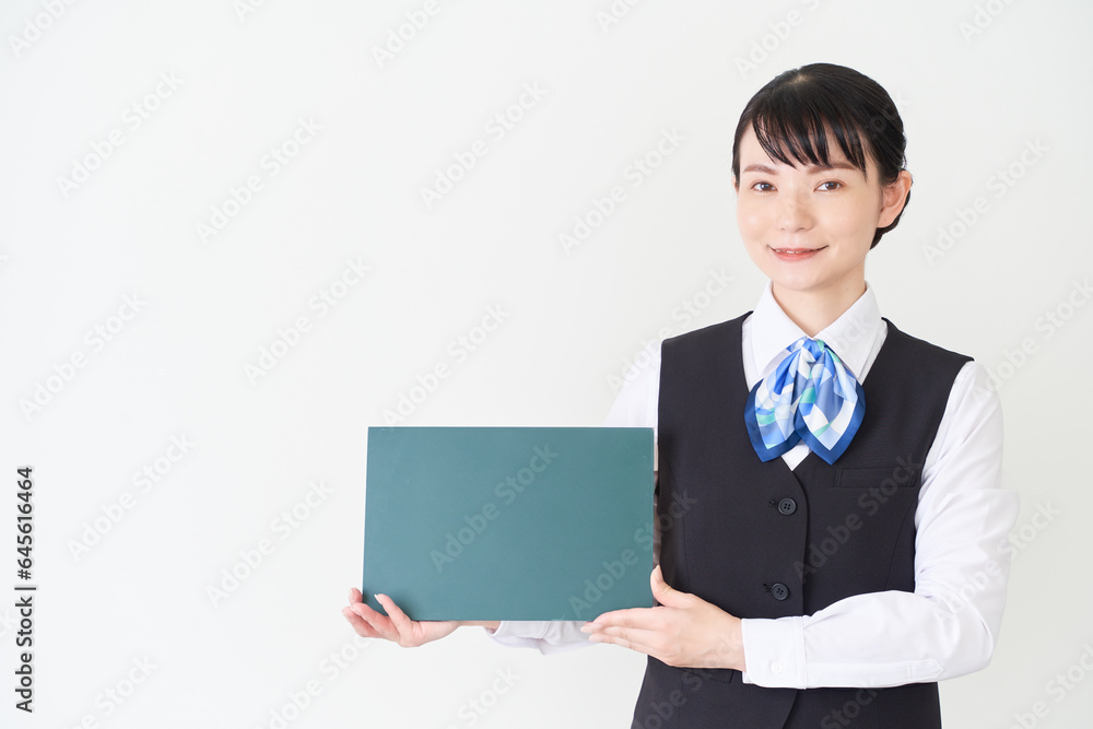黒板を持つベストにリボンタイの制服を着た、受付業務、事務業務の女性 黒板を持つベストにリボンタイの制服を着た、受付業務、事務業務の女性