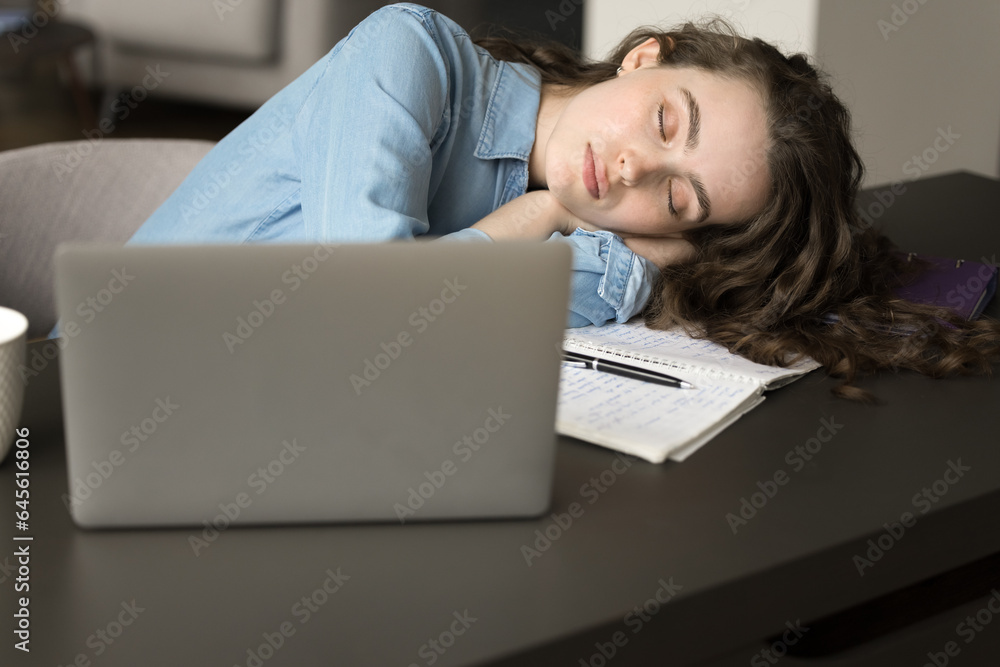 Exhausted young freelance professional girl falling asleep at work desk, placing head with closed eyes on table at laptop computer, feeling extremely tired, facing stress, burnout, deadline Exhausted young freelance professional girl falling asleep at work desk, placing head with closed eyes on table at laptop computer, feeling extremely tired, facing stress, burnout, deadline