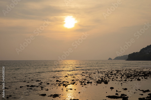 Coastal sunset  orange sky  evening silhouette  calm calm sea shore with light ocean waves  sunlight shining  natural beautiful reflections. summer sky Suitable for recreation  vacation  family fun