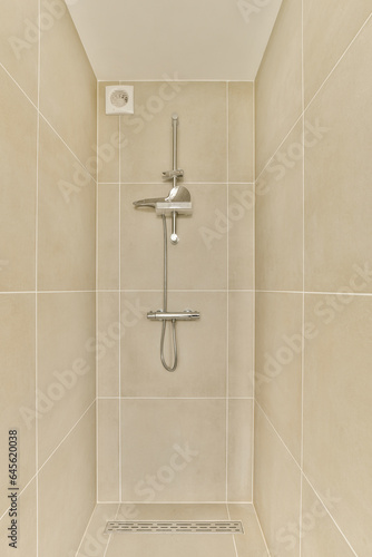 a shower stall in a bathroom with white tiles on the walls, and a metal hand rail attached to the wall