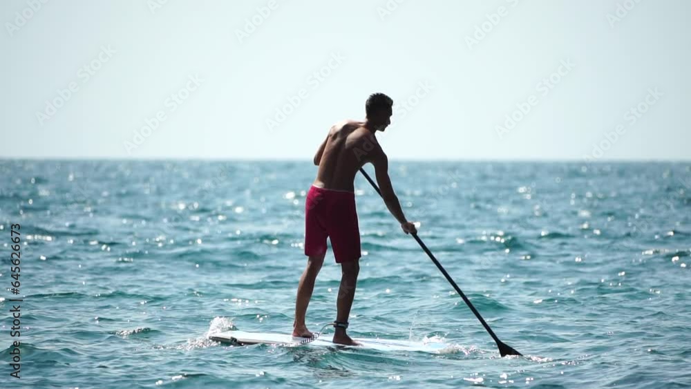 Man Sup Sea. Strong athletic man learns to paddle sup standing on board in open sea ocean on sunny day. Summer holiday vacation and travel concept. Aerial view. Slow motion