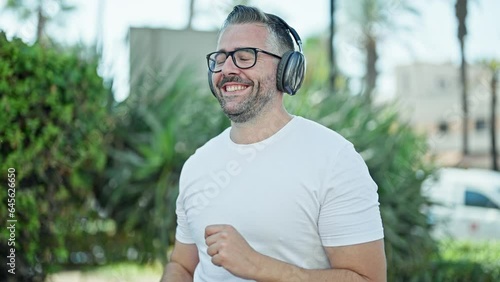Grey-haired man listening to music and dancing at park