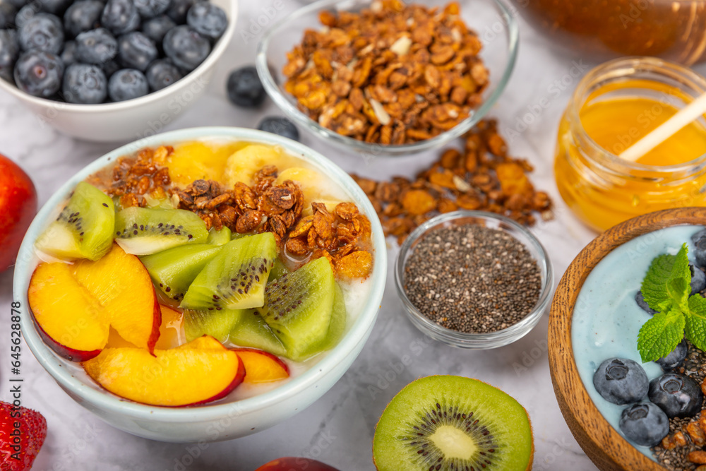 Bowl of granola with yogurt and fresh berries on a texture table. Yogurt berries, acai bowl, spirulina bowl. Healthy food, balanced breakfast. Strawberries, blueberries, kiwi, peach, almonds and chia. Bowl of granola with yogurt and fresh berries on a texture table. Yogurt berries, acai bowl, spirulina bowl. Healthy food, balanced breakfast. Strawberries, blueberries, kiwi, peach, almonds and chia.