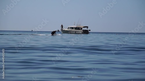 A motorized surfboard with a rider moving on a calm sea. The silhouette of a man on a water scooter glides through the water. Sports and sea activities on a beach holiday. Slow motion. photo