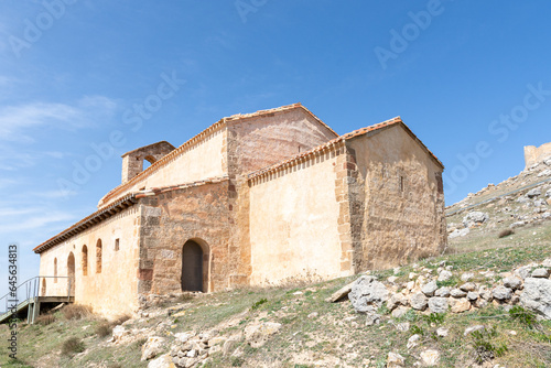 Romanesque hermitage of San Miguel in Gormaz with the caliphal fortress in the background on a sunny day