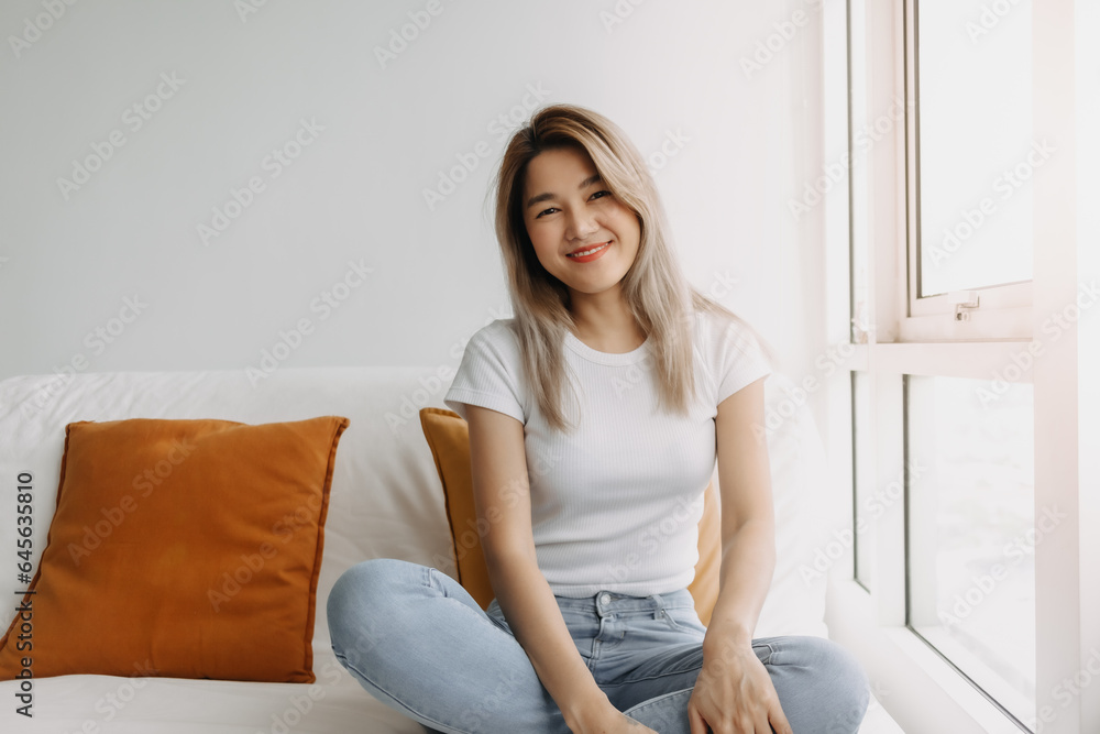 Asian women smiling sitting on sofa looking at the camera at apartment. Asian women smiling sitting on sofa looking at the camera at apartment.