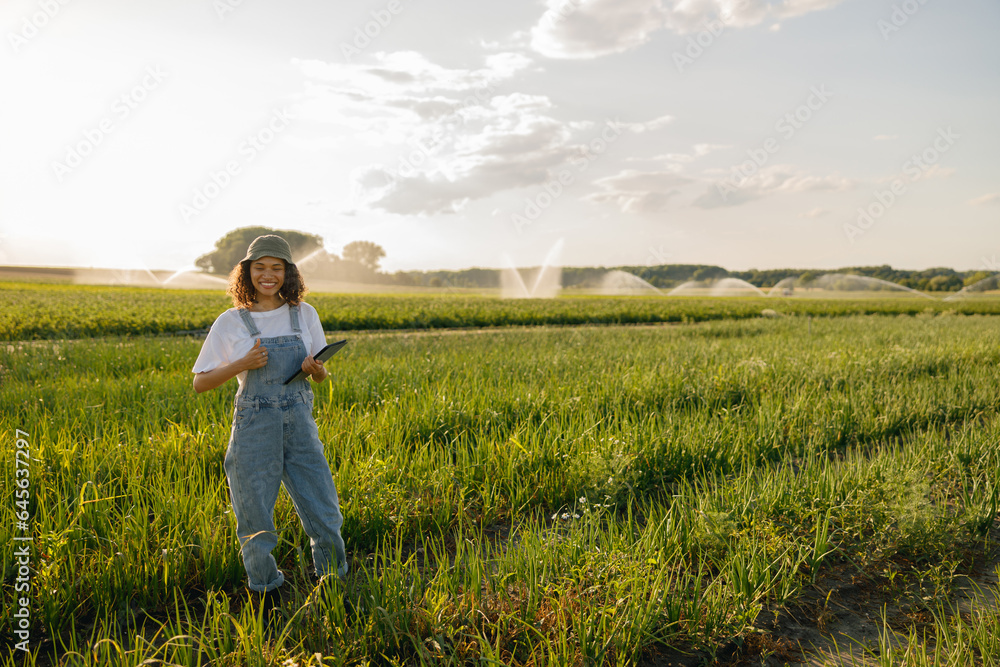 Professional woman farmer in uniform with tablet works in field. Agricultural business concept Professional woman farmer in uniform with tablet works in field. Agricultural business concept