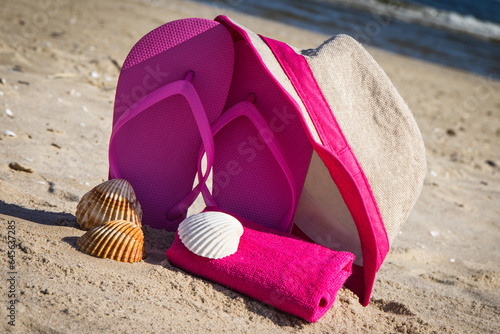 Accessories for relax on beach. Straw hat, flip flop and towel. Summertime