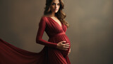 Beautiful pregnant woman in a red dress on a gray background.