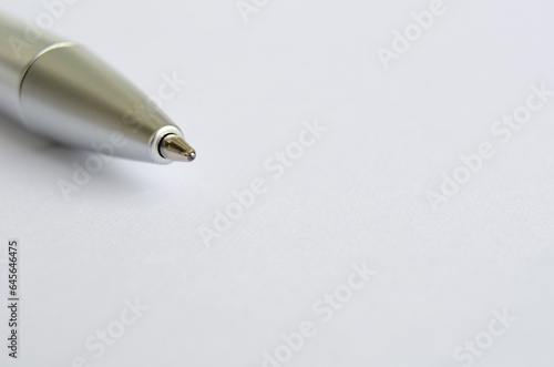 Close-up of metallic pen on white notepad with customizable space for text or ideas.