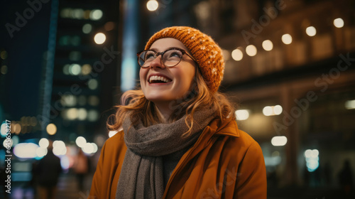 Positive young female in warm clothes and eyeglasses smiling while looking up at lanterns and admiring London city street at night