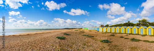 Colorfool beach huts on the shores of Littlehampton Long Beach in Sussex, England, UK; wooden yellow huts on pebbles beach photo