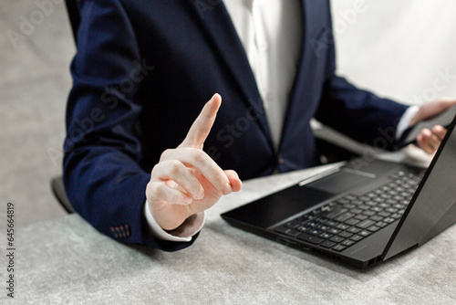 A businessman pointing with his finger and working on a laptop  © MO