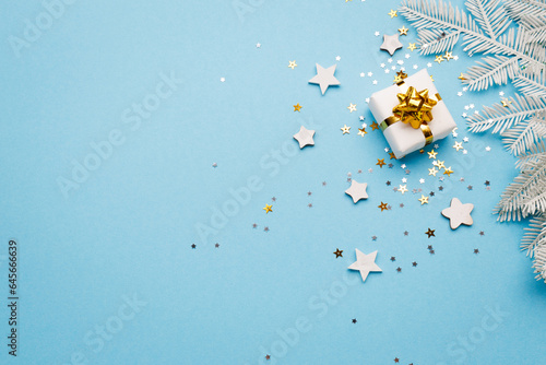 Christmas gift box with decorations and sparkles on blue bacground.