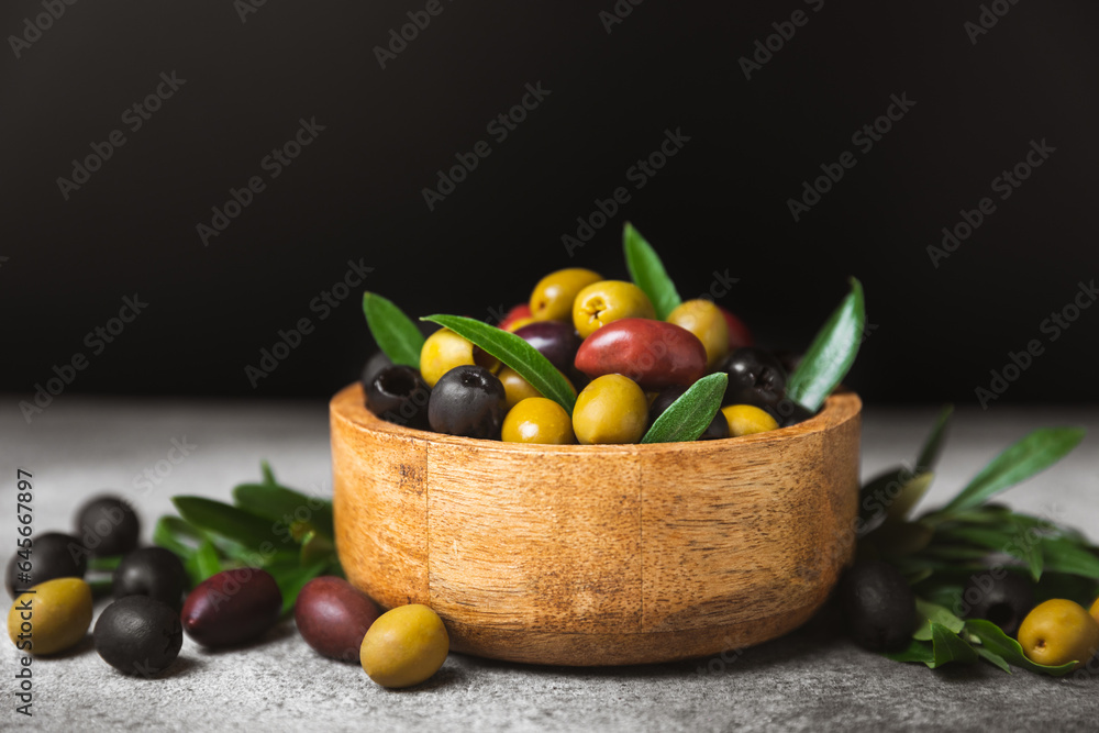 A set of green, red and black olives on a marble background. Various types of olives in bowls and fresh olive leaves. Vegan. Olive fruits. Place for text. Copy space. A set of green, red and black olives on a marble background. Various types of olives in bowls and fresh olive leaves. Vegan. Olive fruits. Place for text. Copy space.