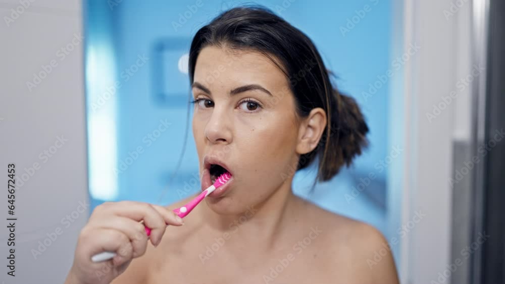 Young beautiful hispanic woman brushing teeth in the bathroom Young beautiful hispanic woman brushing teeth in the bathroom