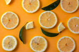 Lemon slices adorned with green leaves on an orange background offer a vivid and tropical display