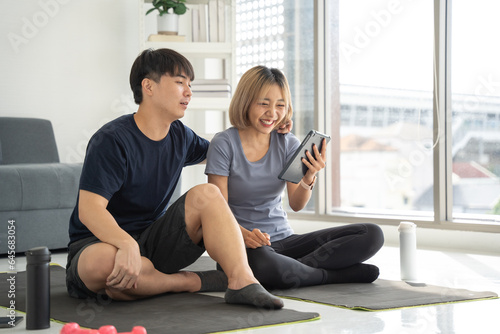Happy asian people sitting on living room together. They looking to smartphone with smiling while rest from exercise at home.