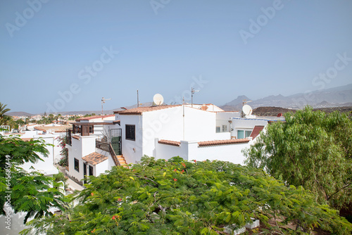 Hot day above the rooftops of a picturesque residence with white villas built in Mediterranean style and surrounded by lush flora in Costa del Silencio, Tenerife, Canary Islands, Spain