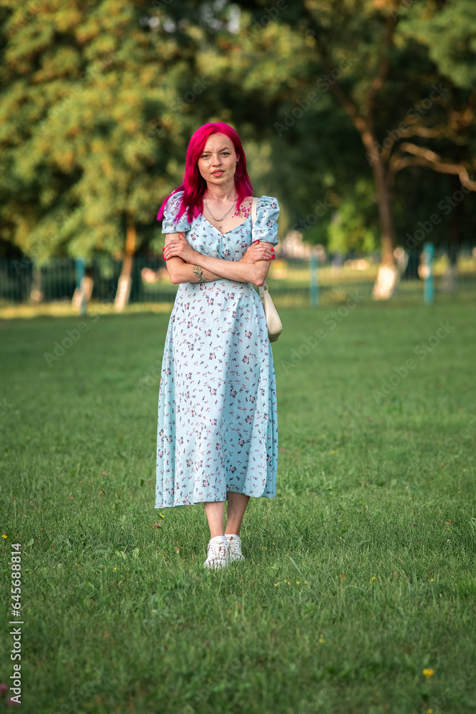 A young beautiful long-haired girl in a dress is spinning in the park. A young beautiful long-haired girl in a dress is spinning in the park.