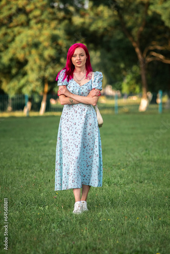 A young beautiful long-haired girl in a dress is spinning in the park.