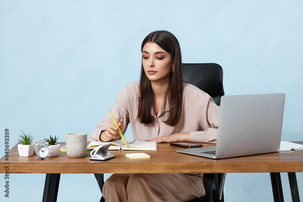 young businesswoman sitting on chair at table and using laptop young businesswoman sitting on chair at table and using laptop