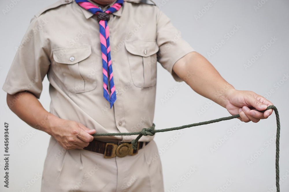 Tying rope knot pattern by put around waist, demonstrated by scout