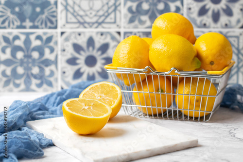 Wire Basket of Fresh Lemons on White Kitchen Counter with Blue Tile Background